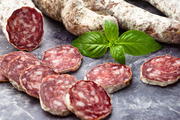 Traditional  thin dried sausage with slices on grey stone background