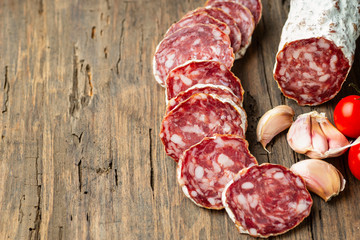 Sliced smoked salami with chilly pepper on wooden background.