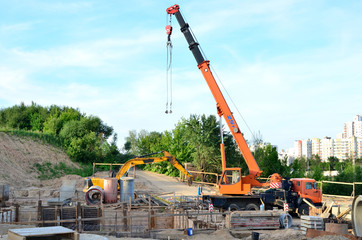 Unloading of cargo and building materials by mobile truck crane at the construction site. Foundation, laying or replacement of underground storm sewer pipes, construction collector