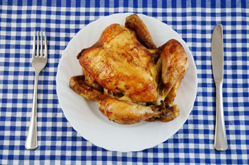 Grilled chicken in white plate on blue tablecloth