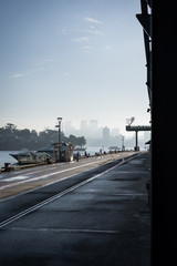 Low angle urbanscape at Jones Bay Wharf. North Sydney visibile in the through the early morning haze in the background. Sydney NSW. June 2019