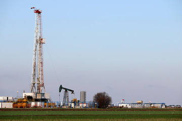 land oil and gas drilling rig and pump jack in oilfield