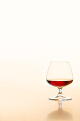 Glass of Cognac on light background with reflection 
