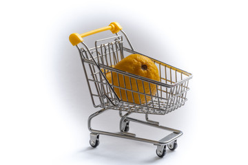 Close-up of shopping carts on white background..Trolley and limon , Sale concept.. Isolated over white background in a cart lies a yellow citrus.