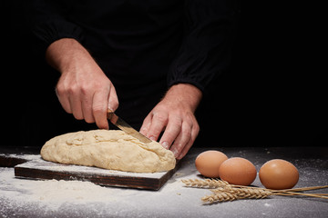 man Baker and his hands over the bread from whole wheat flour (to oven). flour, rustic style