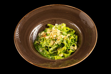 Pasta with spinach and smoked chicken served with creamy sauce isolated at black background.