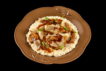 Risotto with duck served with demiglas sauce and parmesan isolated at black backgound.