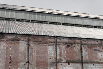 Fototapeta premium Weathered wall and steel roof of an old industrial warehouse, horizontal aspect
