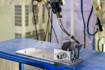 close up workpieces setting on jig fixture with manual quick clamp and torch of electric mig robot welding process at factory