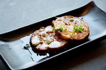 Japanese food style, Selective focus of sliced braised pork on black plate in restaurant (chashu), ready to eat or serve, on dark background