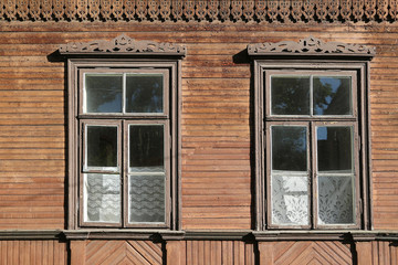 An old wooden windows with carved platbands and carved eaves in a village house.