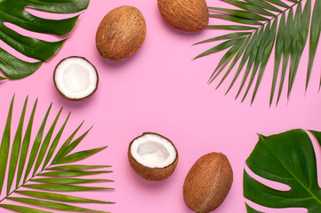 Fototapeta na wymiar Frame of tropical leaves and fresh coconut on pink background. Flat lay, top view, copy space. Summer background, nature. Healthy cooking. Creative healthy food concept, half of coconut