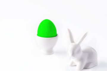 Easter bunny and neon-green Easter egg on a white background. Close up. Selective focus.