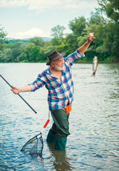 Fishing. Handsome fisherman fishing in a river with a fishing rod. Man fisherman catches a fish.