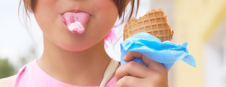 Pretty little brunette girl showing tongue with ice-cream close-up.