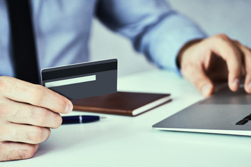 Businessman hands holding credit card and typing on laptop for online shopping and payment makes a purchase on the Internet.