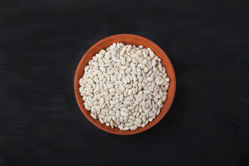 White beans in pottery on a black background. superfood