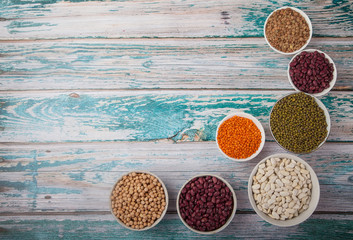 white and red beans, peas, soybean, lentils in porcelain cups on a blue wooden background. Trend Superfood