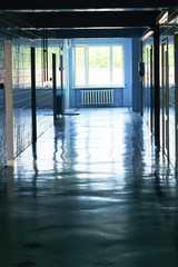 Blurry photo of hospital walk way with bright blue lighting. White floor with cool tone color with light tunnel in the middle of picture.