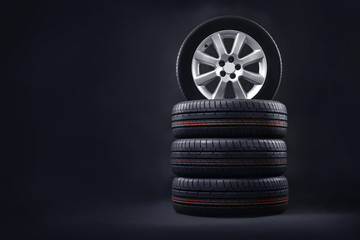 New tires pile on a dark background. Tire fitting background. Copy space. - obrazy, fototapety, plakaty
