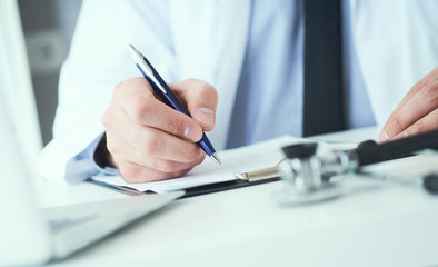 Mid section of male doctor writes prescription to patient at worktable. Panacea and life save, prescribing treatment.