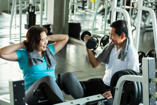 Asian Senior Man And Woman Exercise Lifting Dumbbell And Sit Up In Fitness Gym. Elderly Healthy Lifestyle.