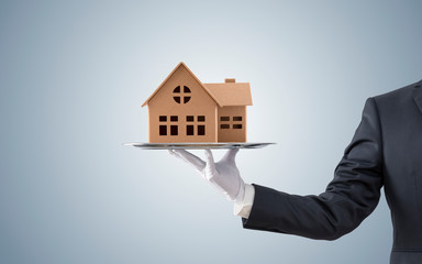 Businessman offering house model on silver tray