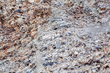 Abstract industrial background with the texture of the surface of a heap of natural multi-colored stone, crushed stone, cobblestone, gravel on a slope in a quarry