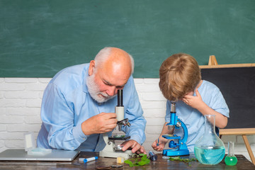 Pupil studying in the classroom. Kid from primary school. Bearded Teacher at school lesson at desks in classroom. Science. Back to school.