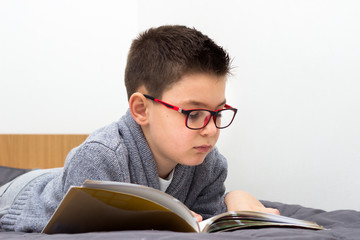 Young boy lying and reading books, Boy studying homework