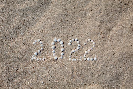 The figure "2022" is laid out on sand with shells. There is free space, space for text.