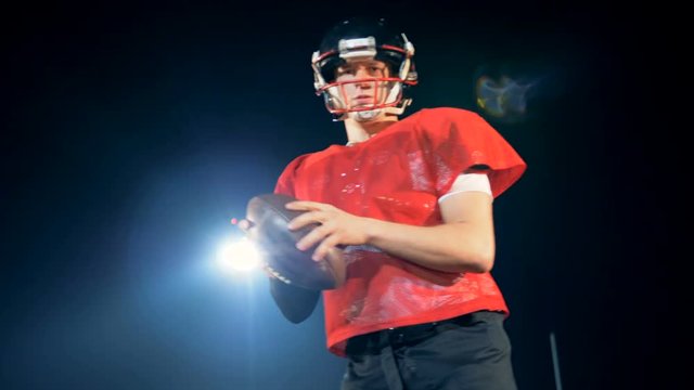 Sportsman in red uniform is preparing to throw a rugby ball