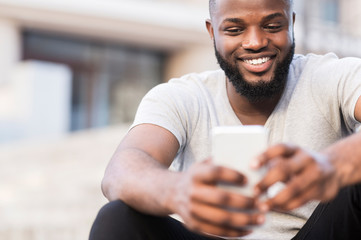 Close up portrait of african guy using cellphone outdoor