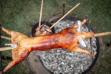 Spanferkel über dem Lagerfeuer gegrillt von einem Wilden auf einer Gartenparty