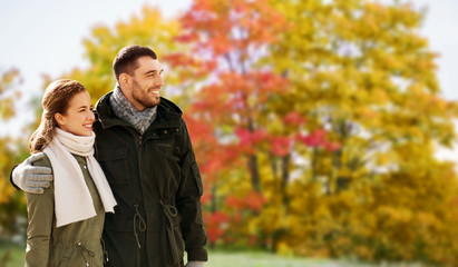 Fototapeta premium love, relationship and people concept - smiling couple hugging over autumn park background