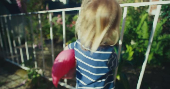 Little toddler with pink flamingo in garden on a sunny summer day
