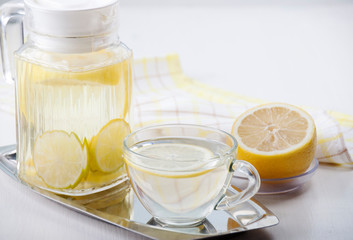   Lemon water in a glass jug and in a glass cup