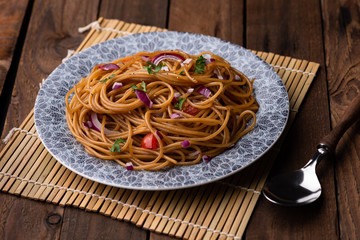 Udon stir fry noodles with vegetables in plate with chopsticks