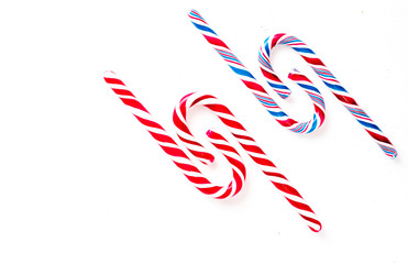 Candy canes on a white surface, top view, place for text