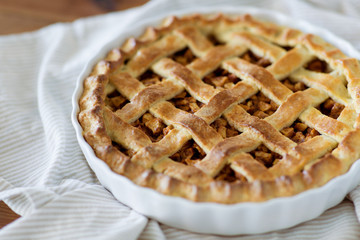 food, culinary and baking concept - close up of apple pie in mold on kitchen towel