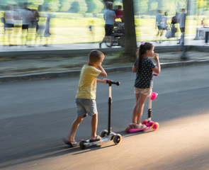 Children riding scooter outdoors. Street urban background