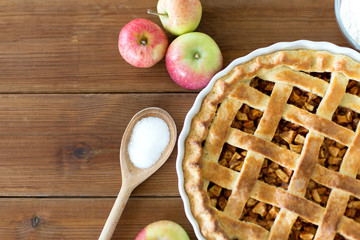 food, culinary and baking concept - close up of apple pie with sugar on wooden table