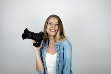 happy blond young woman holding photocamera in her hand smiling isolated white background