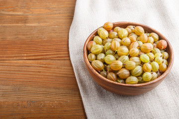 Fresh green gooseberry in wooden bowl on wooden background. side view.