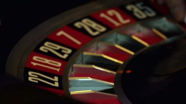 Slow motion shot of a casino croupier spinning the roulette wheel