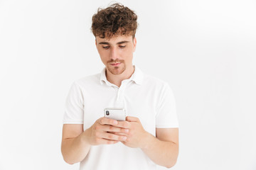 Photo closeup of serious curly man in casual t-shirt holding smartphone and typing