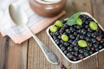 Blackcurrants in the ceramic bowl on a wooden table