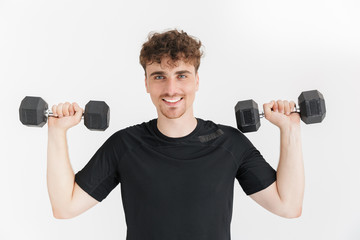 Fototapeta na wymiar Photo closeup of satisfied sporty man in t-shirt looking at camera and lifting dumbbells during workout