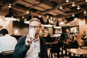 European man blond in a cafe with a glass of coffee enjoys the day.