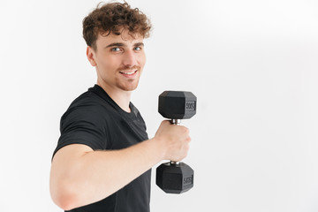 Fototapeta na wymiar Photo closeup of muscular sporty man in t-shirt looking at camera and lifting dumbbell during workout